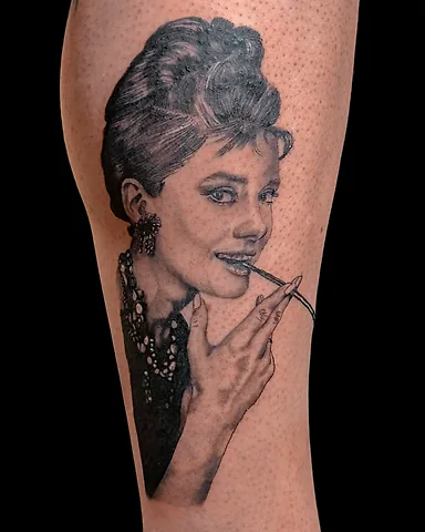 Realistic black and grey Audrey Hepburn portrait calf tattoo, by Domi (based in Coventry, UK)