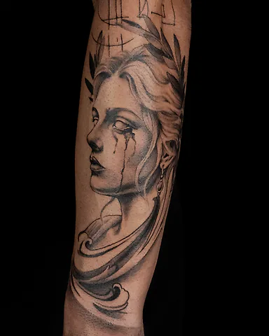 Black and grey Greek goddess statue with laurel wreath and tears forearm tattoo, by Domi (based in Coventry, UK)