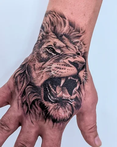 Realistic black and grey roaring lion hand tattoo, by Domi (based in Coventry, UK)
