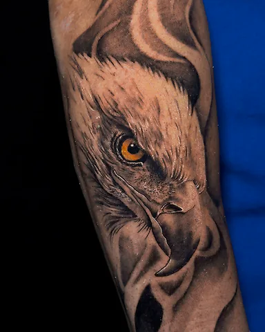 Realistic black and grey eagle forearm tattoo with amber eye, by Domi (based in Coventry, UK)