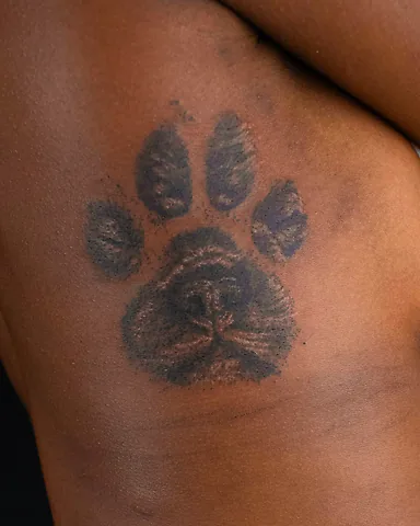 Realistic black and grey dog paw print rib tattoo, by Domi (based in Coventry, UK)