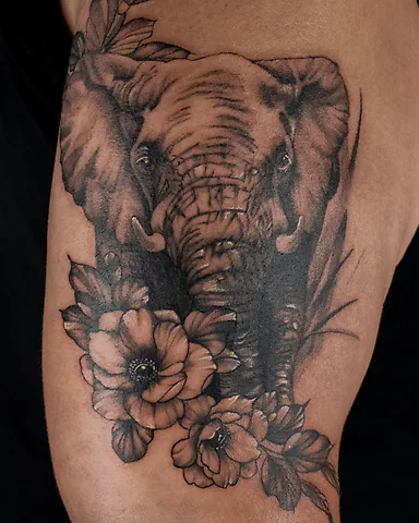 Realistic black and grey elephant and flowers upper arm tattoo, by Domi (based in Coventry, UK)
