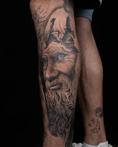 Realistic black and grey Viking warrior portrait calf tattoo, by Domi (based in Coventry, UK)
